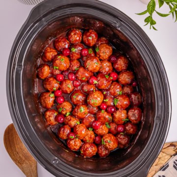 A slow cooker filled with cranberries and meatballs.