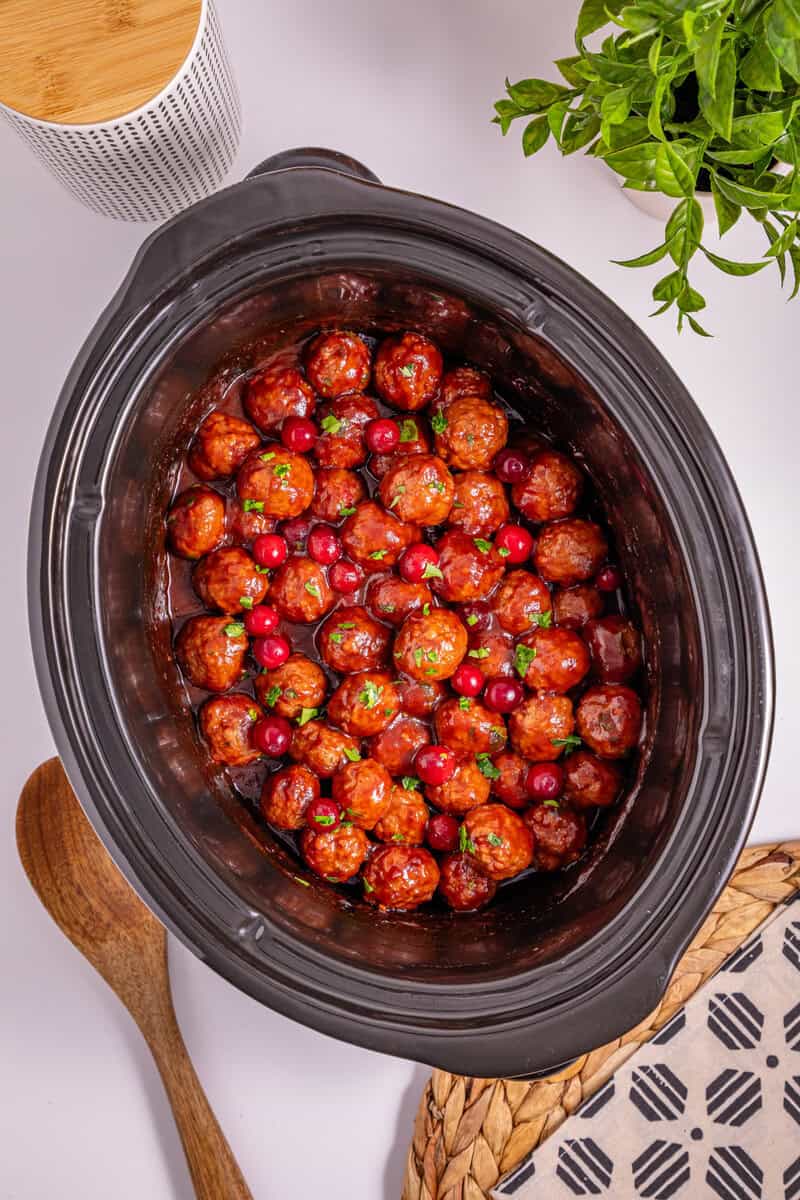 A slow cooker filled with cranberries and meatballs.