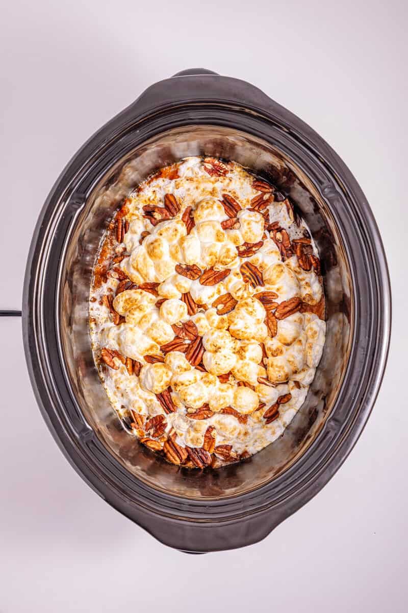 Slow cooker sweet potato casserole topped with marshmallows and pecans.