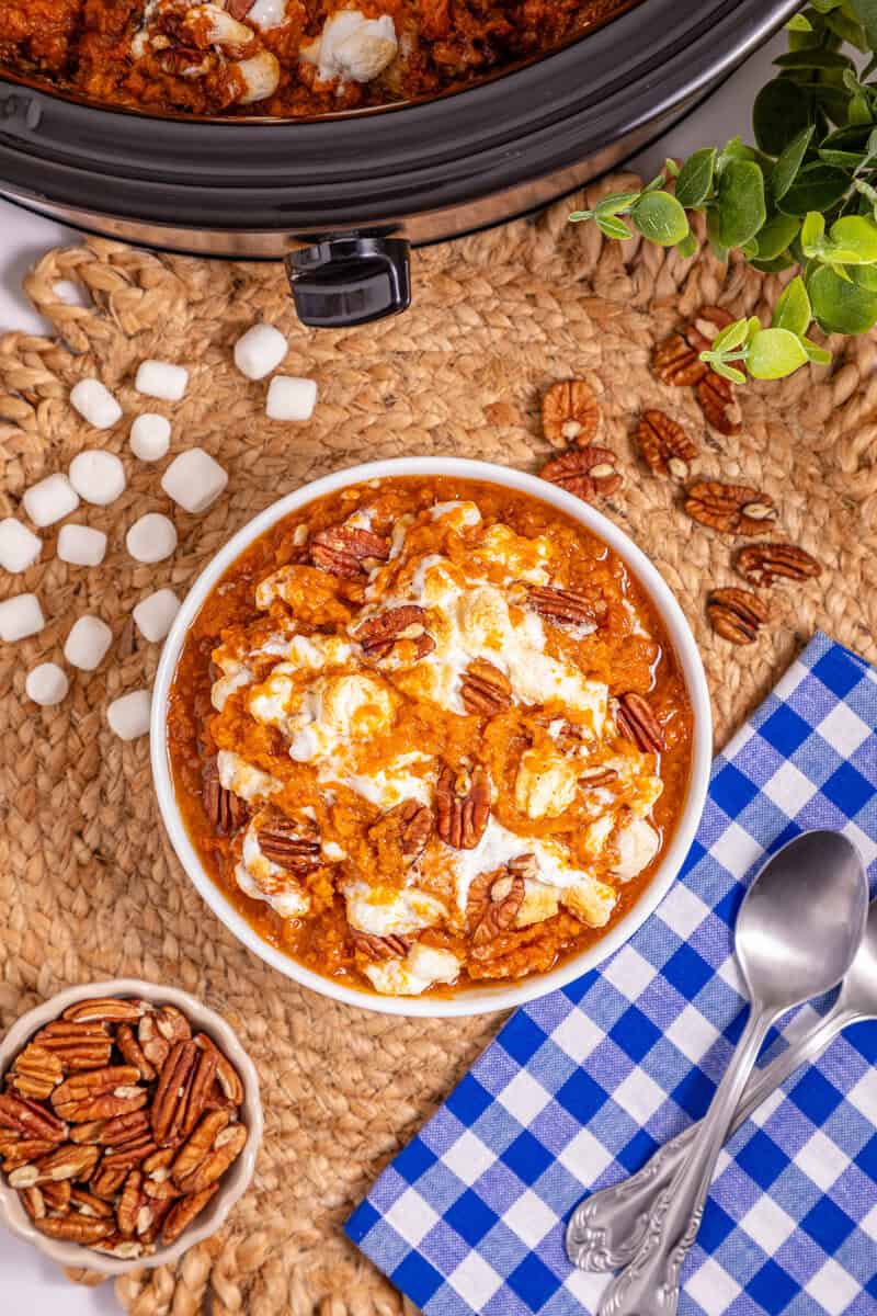 A bowl of sweet potato casserle topped with toasted marshmallows and pecans.