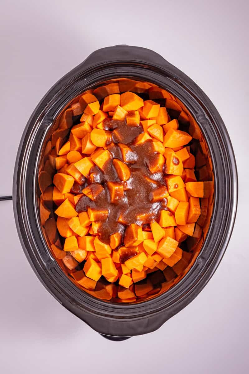 Diced sweet potatoes and a cinnamon sauce in a slow cooker.