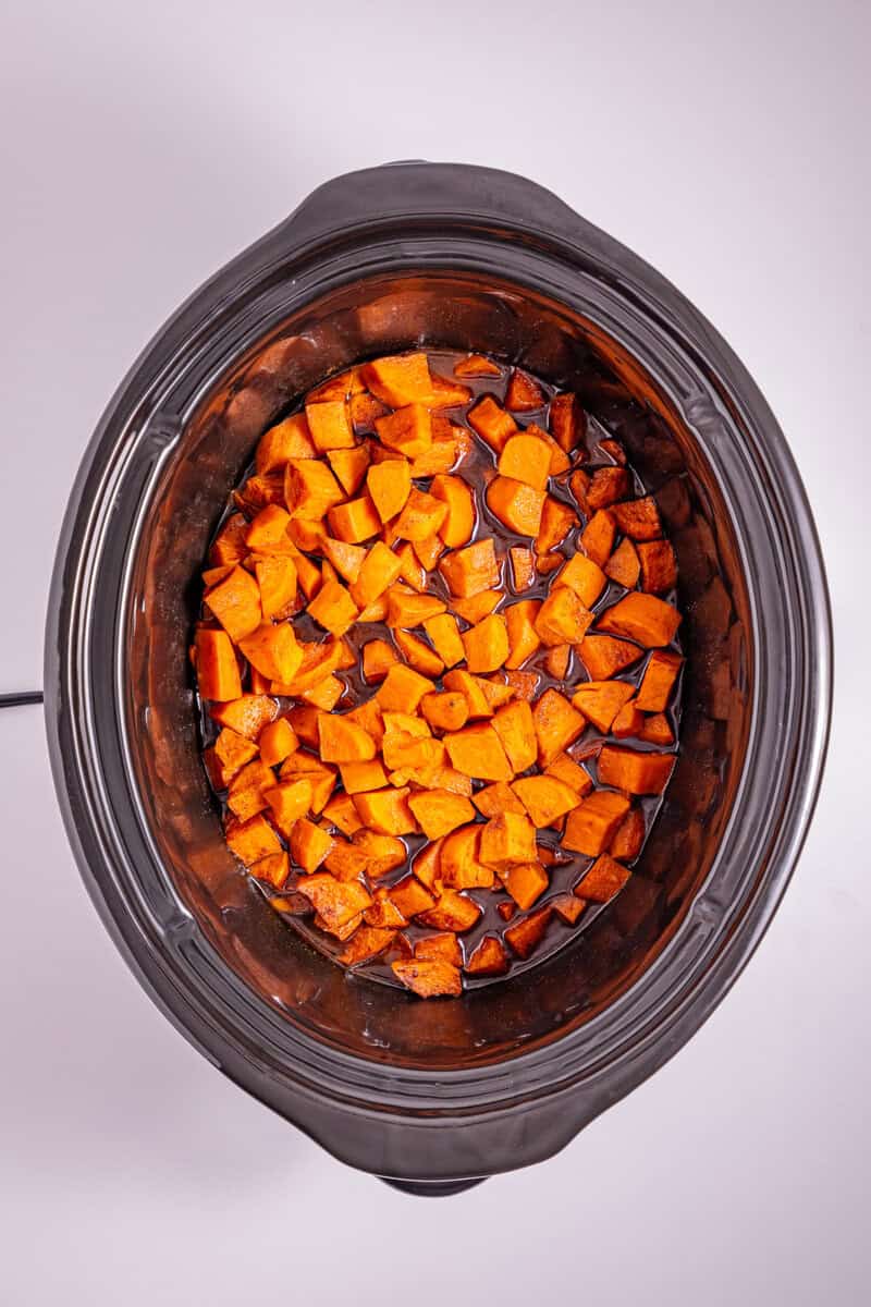 Cubed sweet potatoes in a brown sugar sauce in the slow cooker.