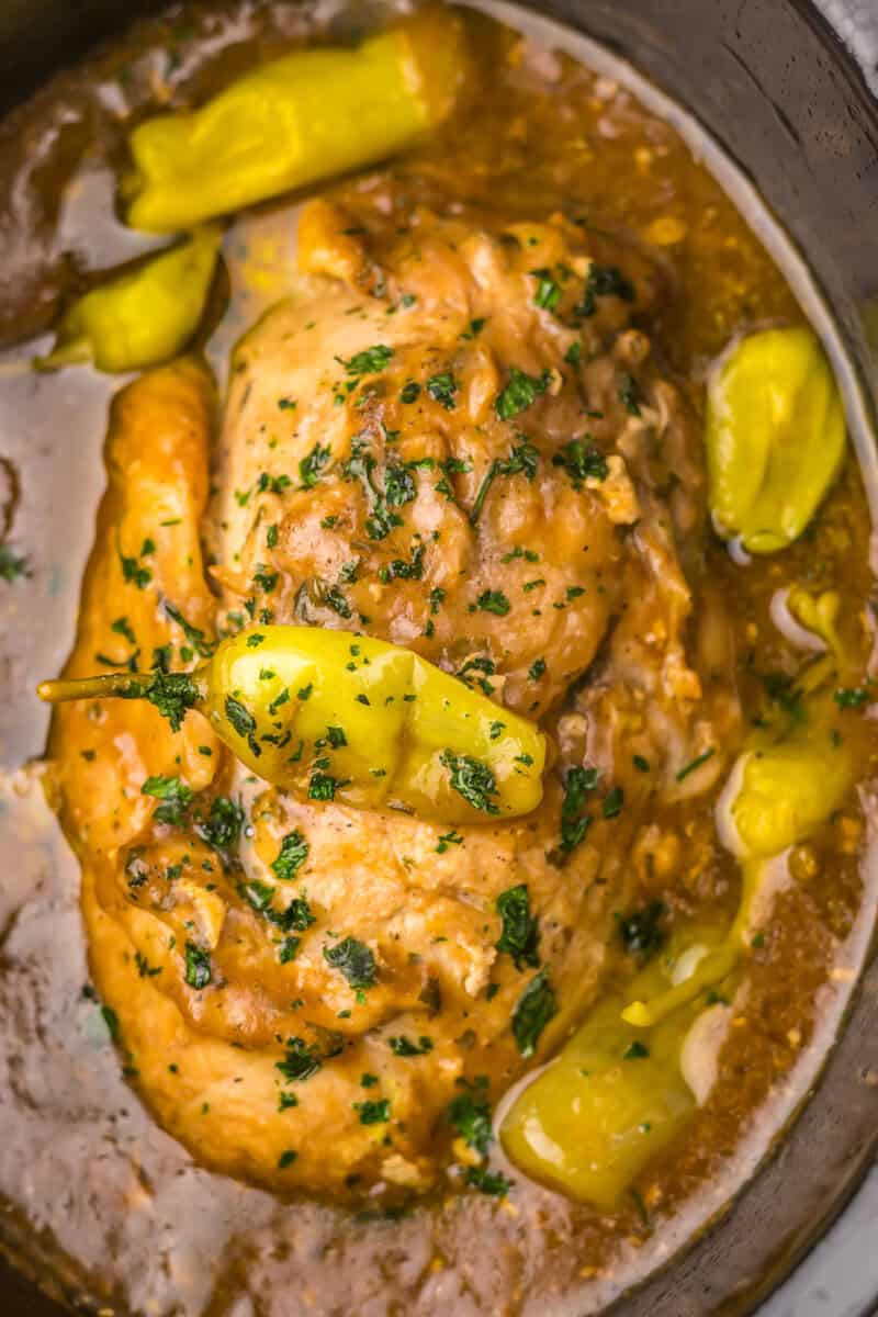 Mississippi turkey breast in a slow cooker topped with pepperoncini peppers.